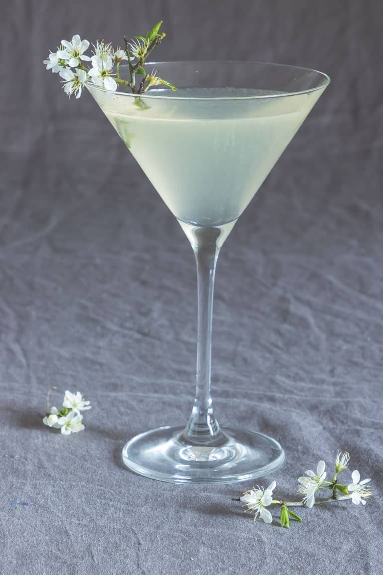 closeup of lemon drop martini on drop cloth surrounded by flowers