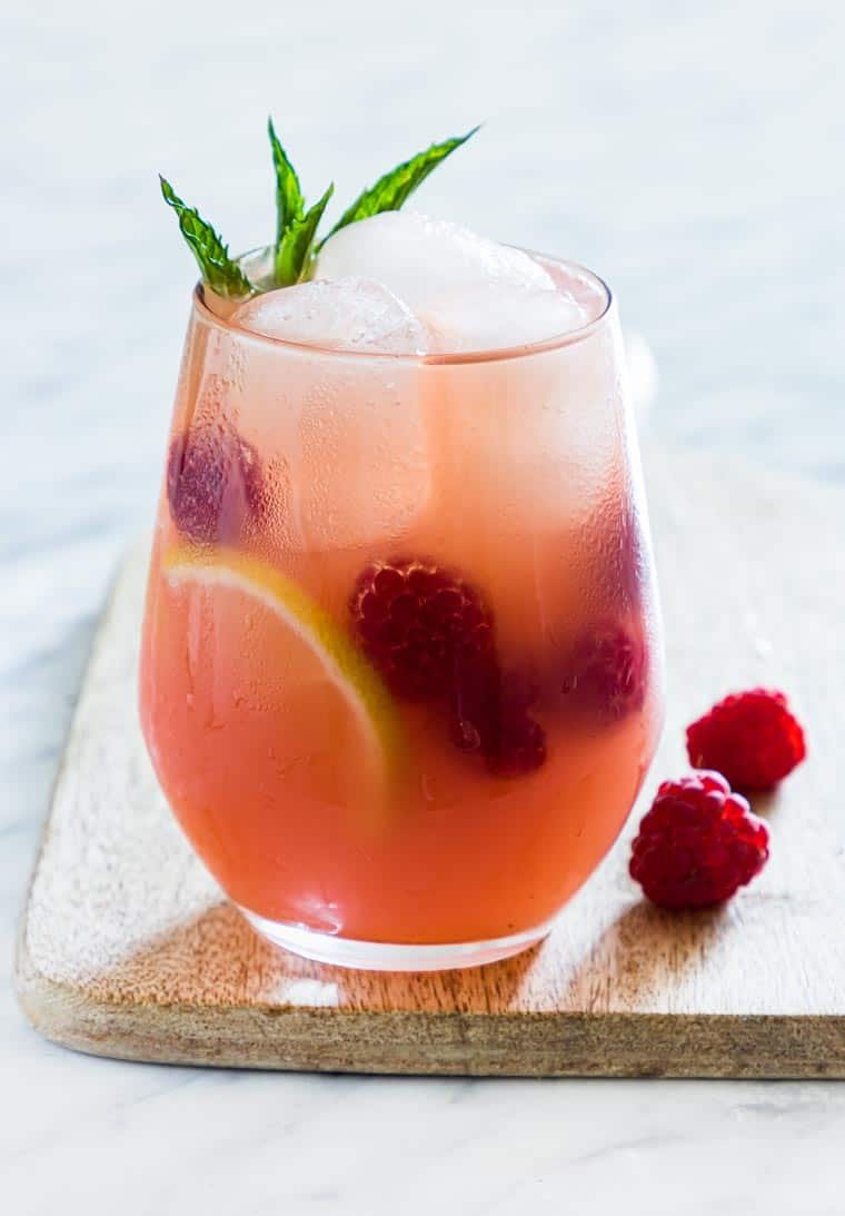 a glass of raspberry vodka lemonade garnished with mint and raspberries