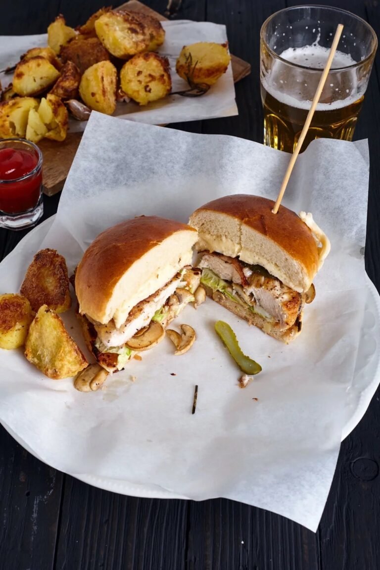 chicken burger made with mushrooms and cheese sauce cut in half and served with chips