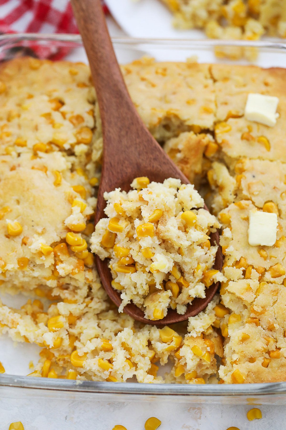 Cornbread casserole served in a casserole dish with a wooden spoon scooped.