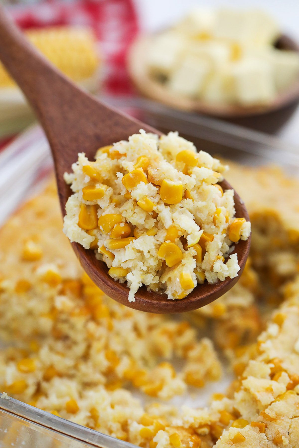 Cornbread casserole scooped into a wooden spoon.