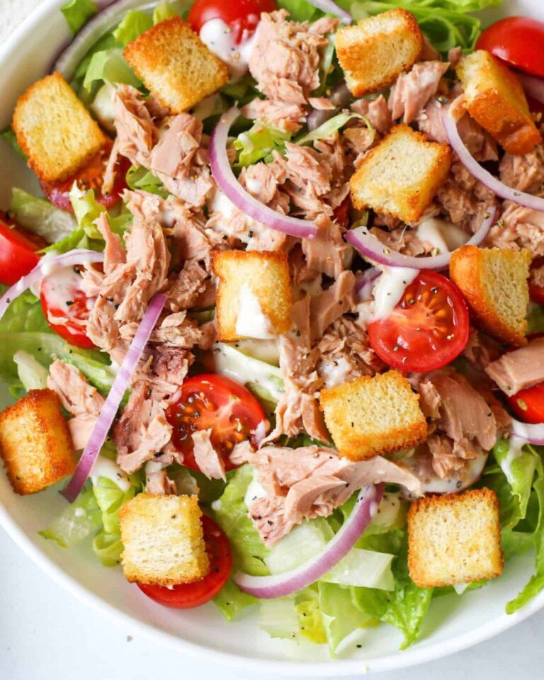 Close up view of Tuna Caesar Salad in a white salad bowl.