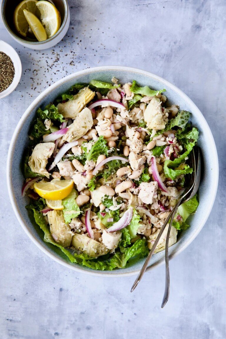 Tuna White Bean Salad with Artichokes in a white bowl with serving spoons.