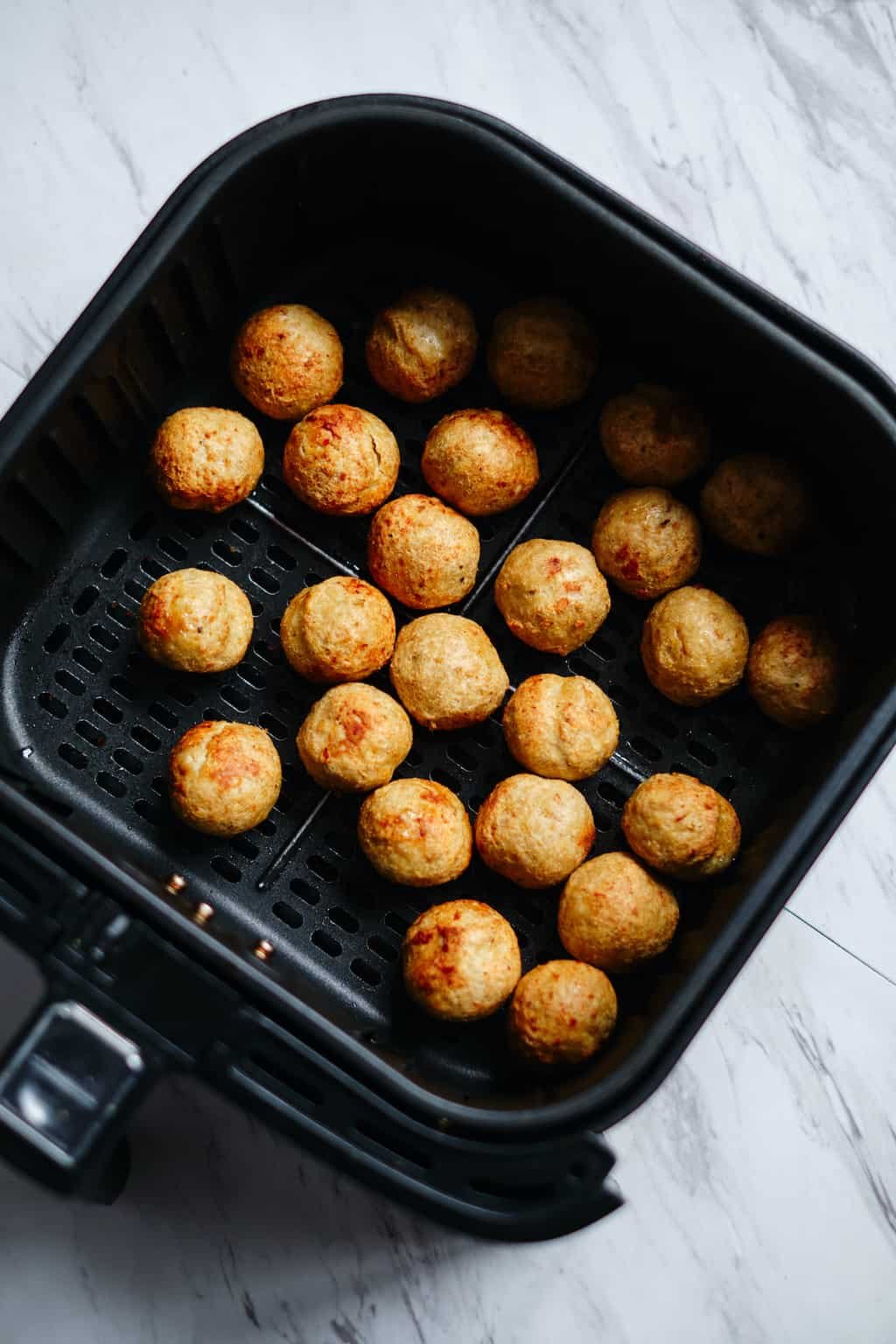 top down view of frozen meatballs in air fryer basket