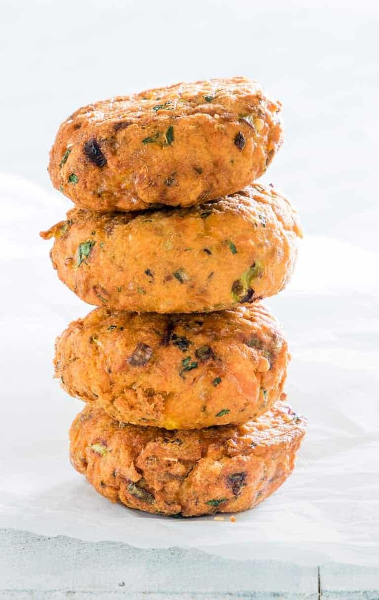 close up view of four air fryer salmon patties stacked in top of each other on a table