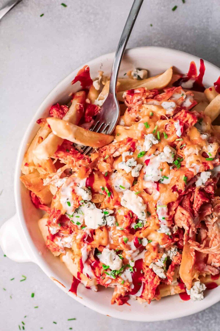 Buffalo chicken fries on white plate with a fork in it.