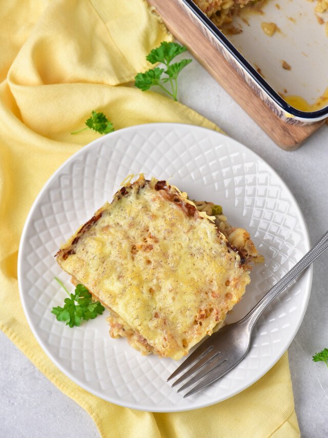 a serving of cheesy tuna casserole on a white plate with a fork