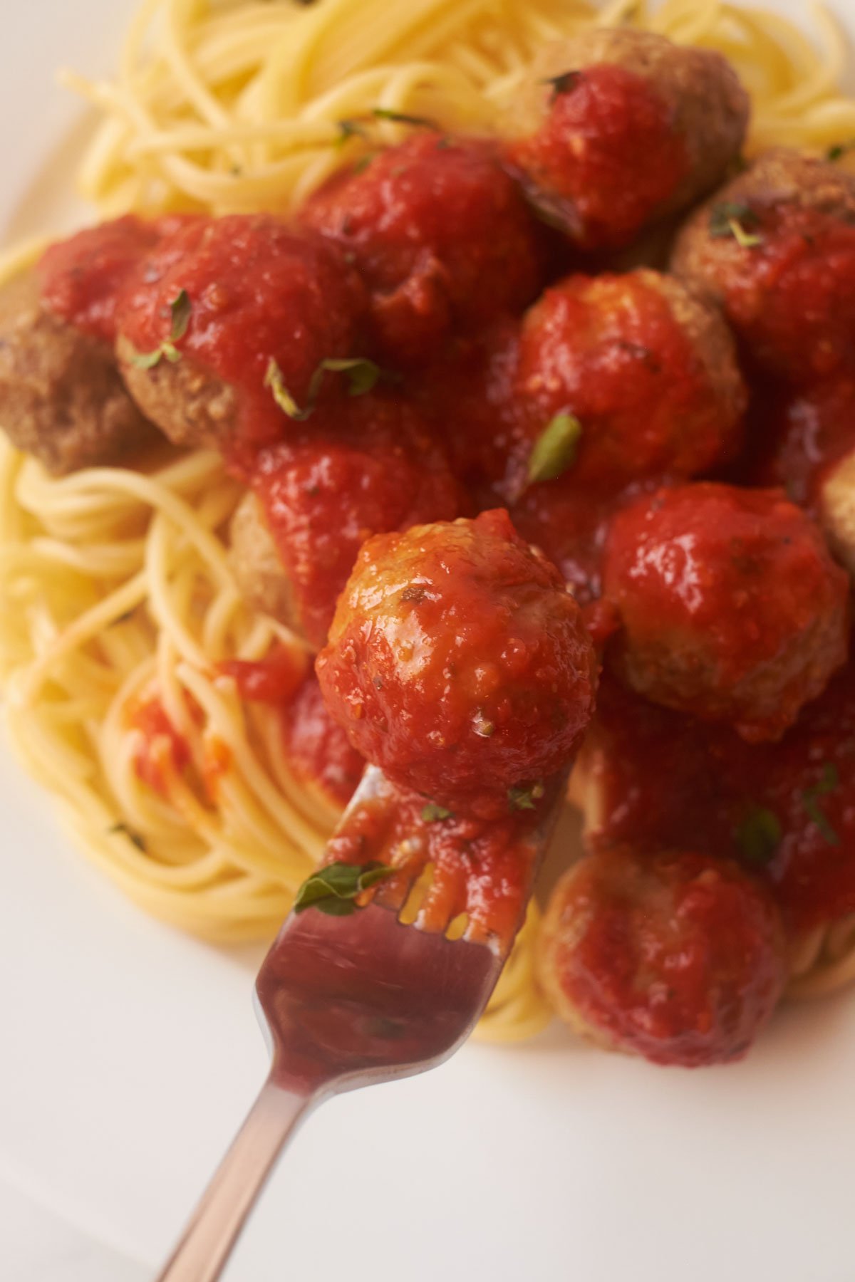 a fork removing one of the cooked frozen meatballs from a plate