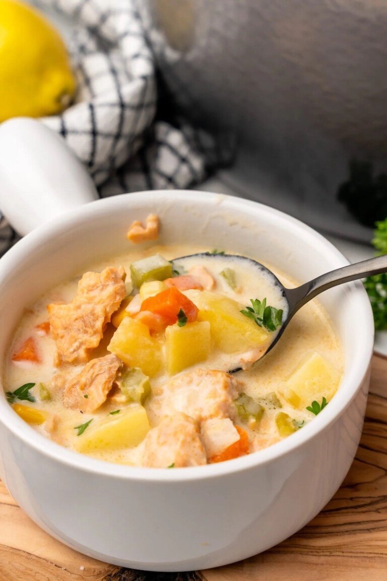 a bowl of salmon chowder with a spoon removing one bite